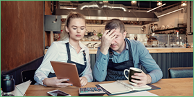 Coface Focus - the business insolvency paradox in Europe: miracle and mirage. The photo shows a man and a woman in a café worried about their corporate finances.