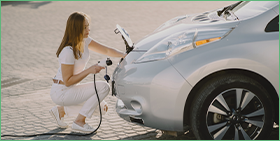 Le boom des métaux liés aux véhicules électriques est-il durable ? La photo montre une femme qui branche une voiture électrique à une source d'énergie.