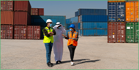 Communiqué de presse pour le Focus de Coface sur les perspectives pour les Emirats Arabes Unis après la crise de COVID-19. L'image montre deux hommes d'affaires et une femme d'affaires discutant dans un parc à conteneurs.