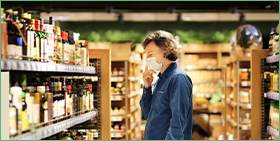 Coface Focus: Is de mondiale detailhandel weer normaal geworden? Op de foto ziet u een man met een mondmasker die in een supermarkt alcoholische producten doorbladert